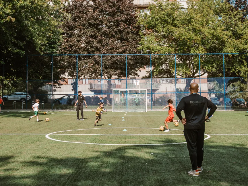 Football field with building behind it, a few kids playing